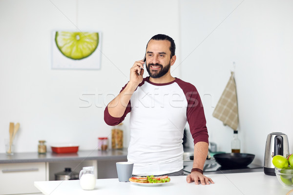 man calling on smartphone and eating at home Stock photo © dolgachov
