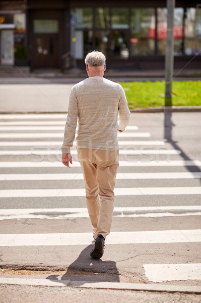 senior man walking along city crosswalk Stock photo © dolgachov