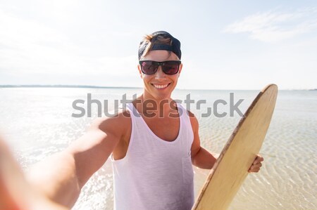 happy young man with skimboard on summer beach Stock photo © dolgachov
