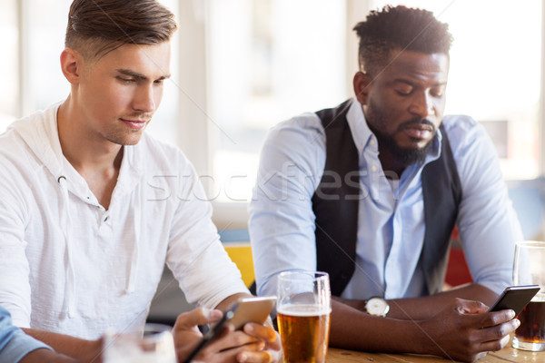 male friends with smartphone drinking beer at bar Stock photo © dolgachov