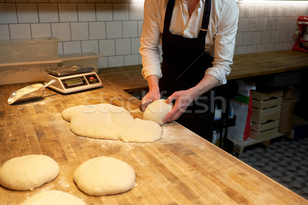 baker portioning dough with bench cutter at bakery Stock photo © dolgachov