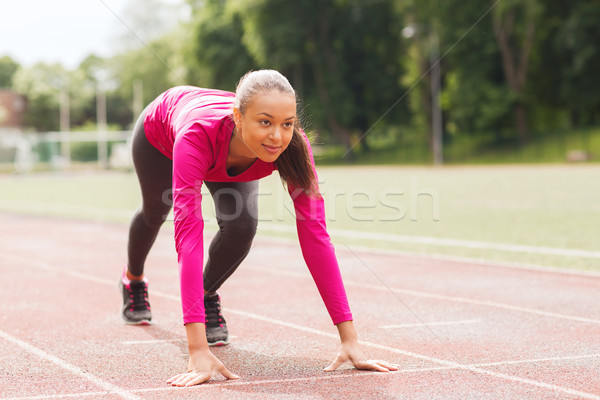 smiling young woman running on track outdoors Stock photo © dolgachov