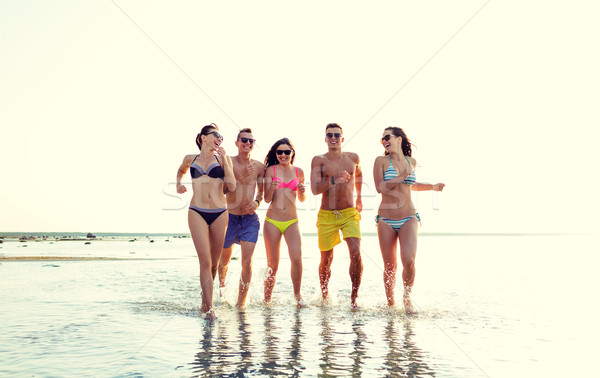 smiling friends in sunglasses running on beach Stock photo © dolgachov