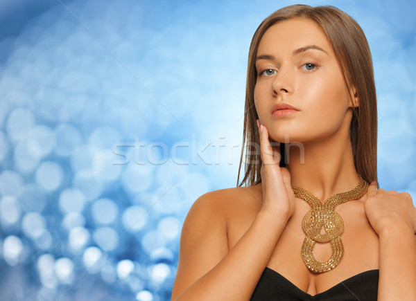 woman wearing golden necklace over blue lights Stock photo © dolgachov