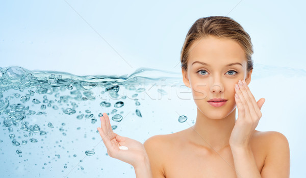 young woman applying cream to her face Stock photo © dolgachov