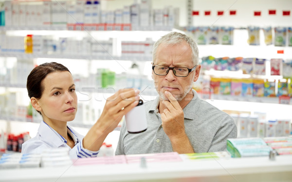 pharmacist showing drug to senior man at pharmacy Stock photo © dolgachov