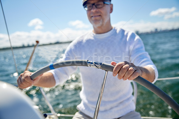 senior man at helm on boat or yacht sailing in sea Stock photo © dolgachov