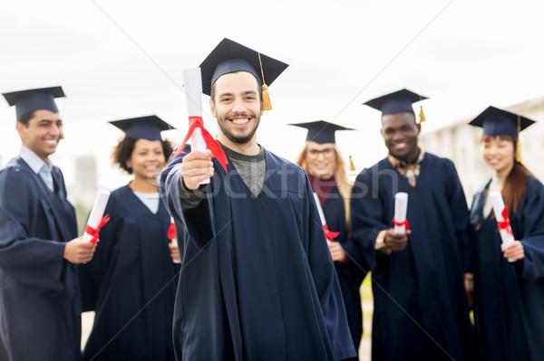 happy students in mortar boards with diplomas Stock photo © dolgachov