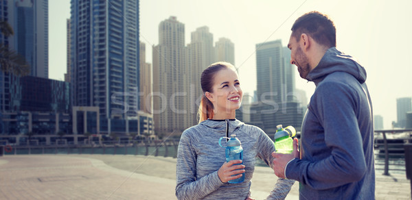 smiling couple with bottles of water in city Stock photo © dolgachov