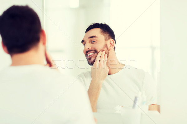 happy young man applying cream to face at bathroom Stock photo © dolgachov