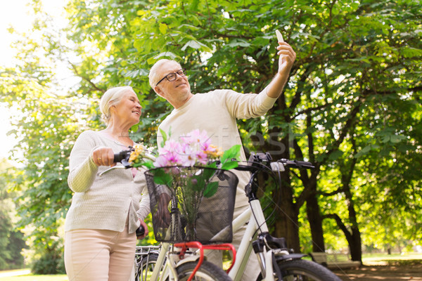 Stock photo: senior couple with bicycles taking selfie at park