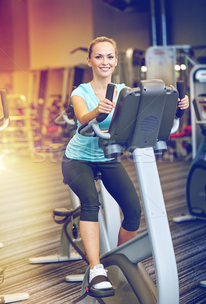 smiling woman exercising on exercise bike in gym Stock photo © dolgachov