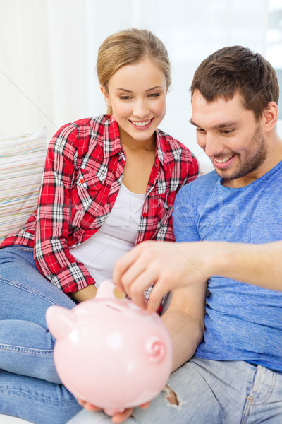 smiling couple with piggybank sitting on sofa Stock photo © dolgachov