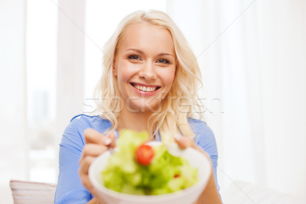 Stock photo: smiling young woman with green salad at home