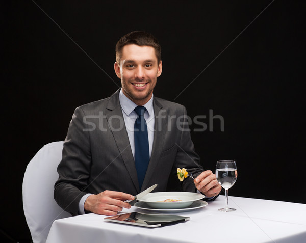 smiling man with tablet pc eating main course Stock photo © dolgachov