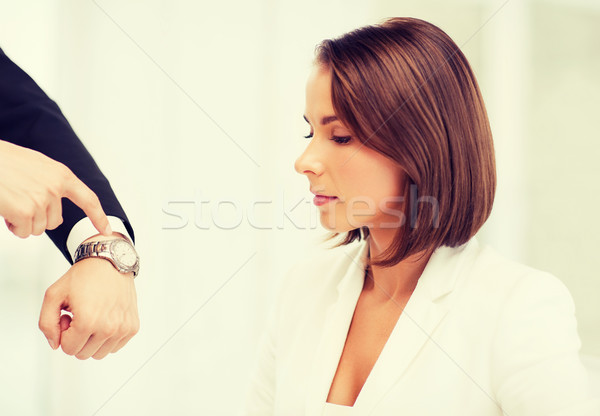 boss showing time to stressed businesswoman Stock photo © dolgachov