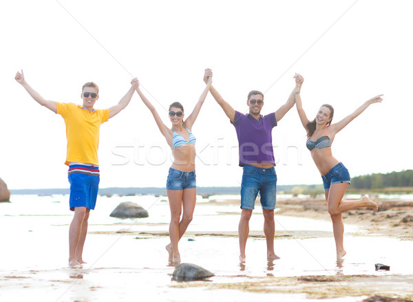 group of happy friends holding hands on beach Stock photo © dolgachov