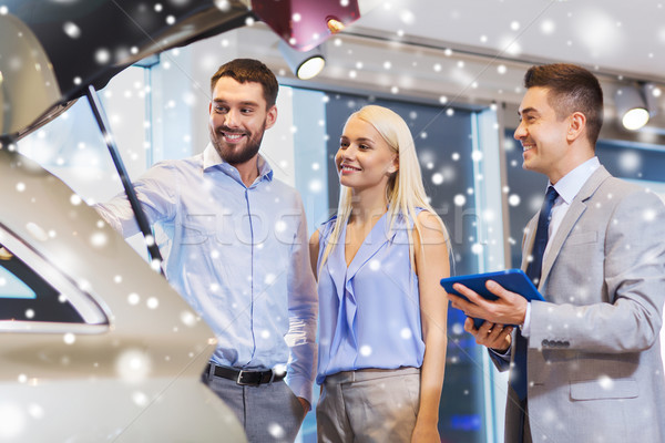 happy couple with car dealer in auto show or salon Stock photo © dolgachov