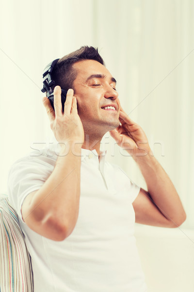 happy man in headphones listening to music at home Stock photo © dolgachov