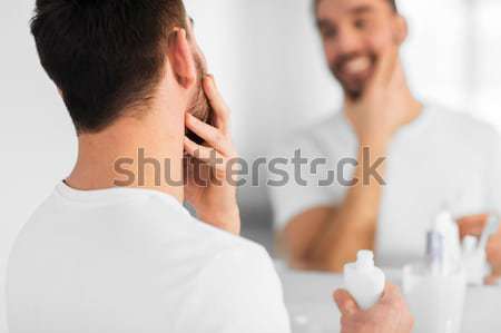 close up of man applying cream to face at bathroom Stock photo © dolgachov