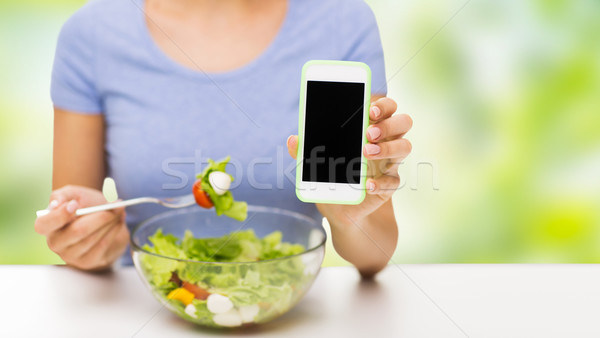 close up of woman with smartphone eating salad Stock photo © dolgachov