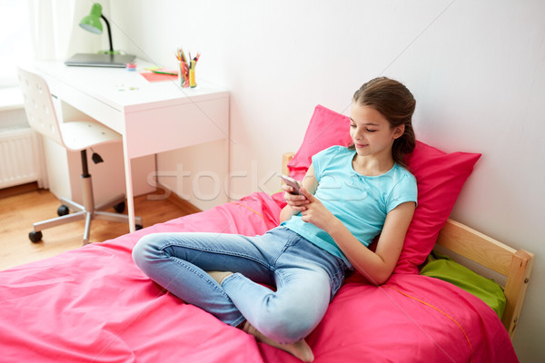smiling girl texting on smartphone at home Stock photo © dolgachov
