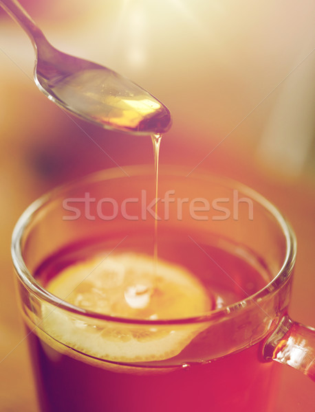 close up of woman adding honey to tea with lemon Stock photo © dolgachov