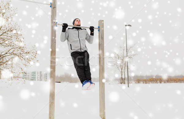 young man exercising on horizontal bar in winter Stock photo © dolgachov