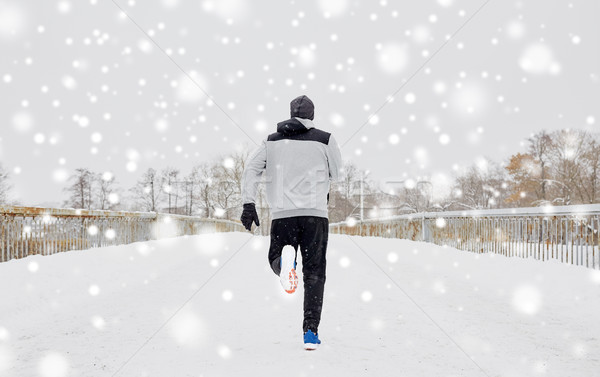 man running along snow covered winter bridge road Stock photo © dolgachov