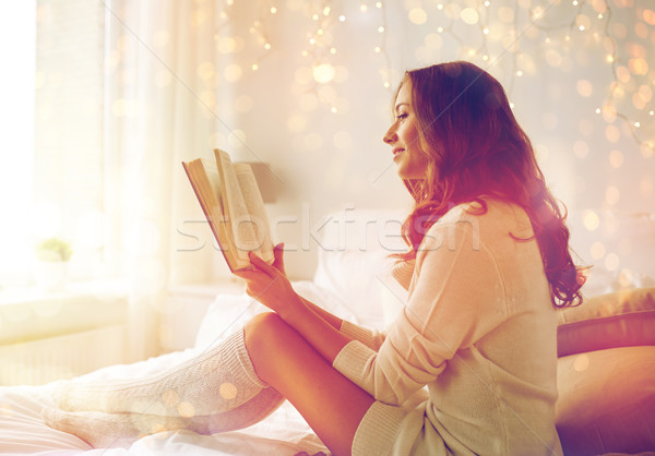 happy young woman reading book in bed at home Stock photo © dolgachov