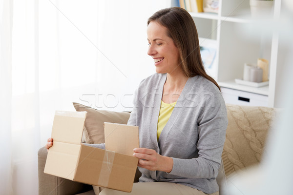 smiling woman opening parcel box at home Stock photo © dolgachov