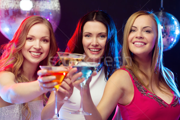 three smiling women with cocktails and disco ball Stock photo © dolgachov