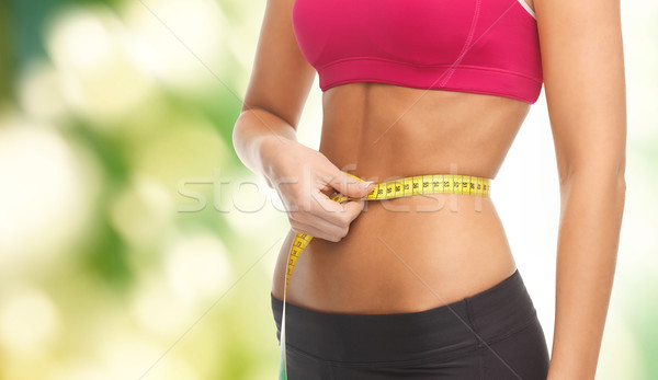 Stock photo: close up trained belly with measuring tape