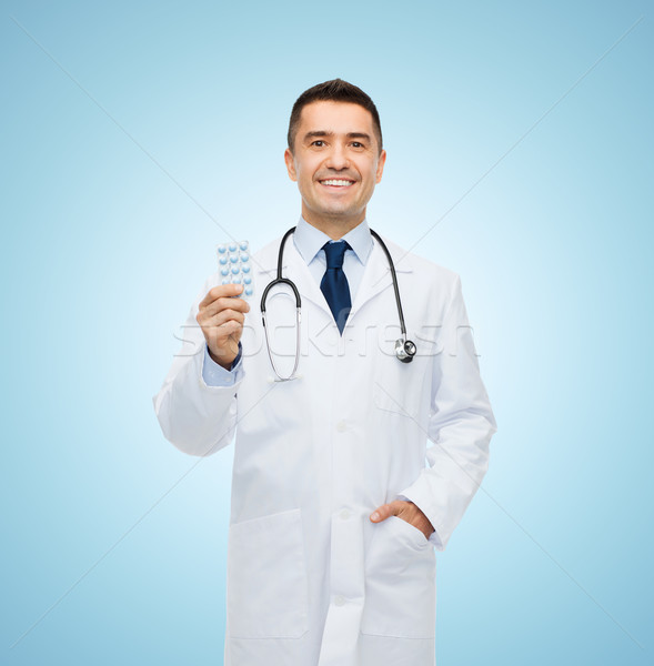 smiling male doctor in white coat with tablets Stock photo © dolgachov