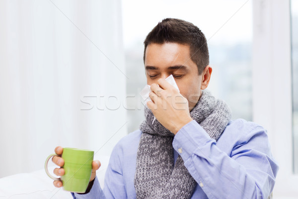 ill man with flu drinking tea and blowing nose Stock photo © dolgachov