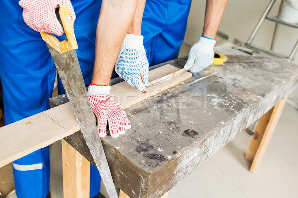 close up of builders with arm saw sawing board Stock photo © dolgachov