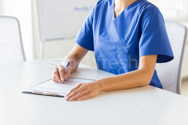 Stock photo: close up of doctor or nurse writing to clipboard