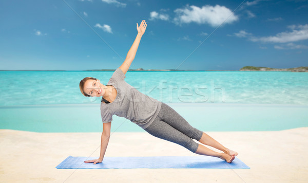 woman making yoga in side plank pose on beach  Stock photo © dolgachov