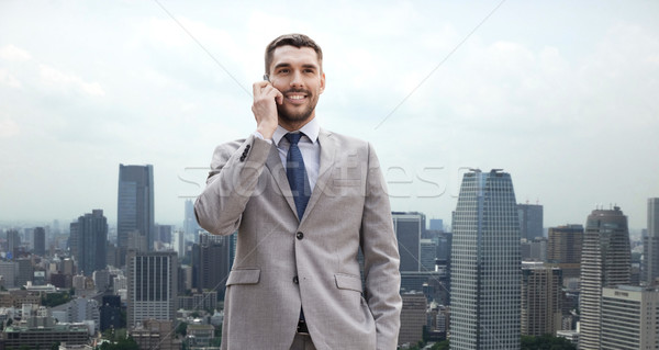 smiling businessman with smartphone in city Stock photo © dolgachov