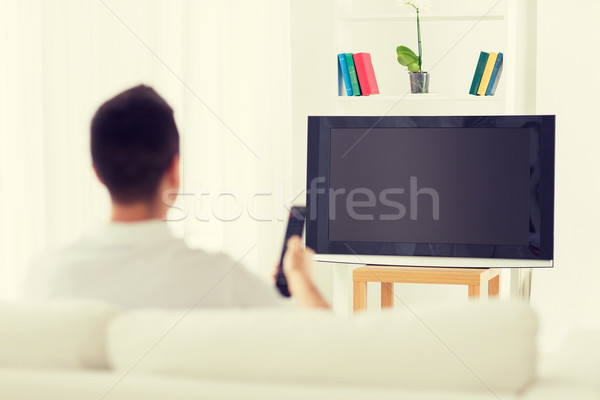 man watching tv and changing channels at home Stock photo © dolgachov