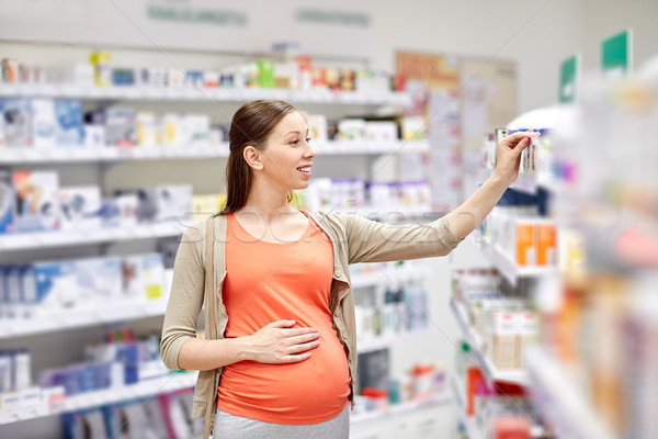 happy pregnant woman choosing medicine at pharmacy Stock photo © dolgachov