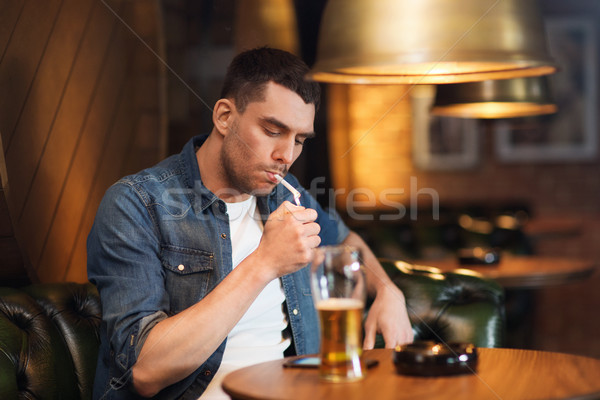 man drinking beer and smoking cigarette at bar Stock photo © dolgachov