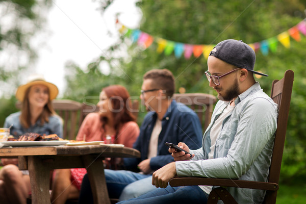 man with smartphone and friends at summer party Stock photo © dolgachov