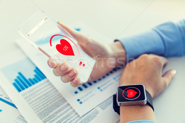 Stock photo: hands with heart icon on smartphone and smartwatch