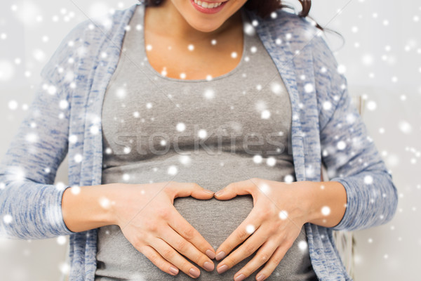 close up of happy pregnant woman making heart Stock photo © dolgachov