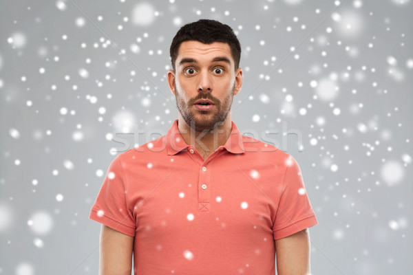 surprised man in polo t-shirt over snow background Stock photo © dolgachov