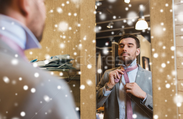 man tying tie on at mirror in clothing store Stock photo © dolgachov