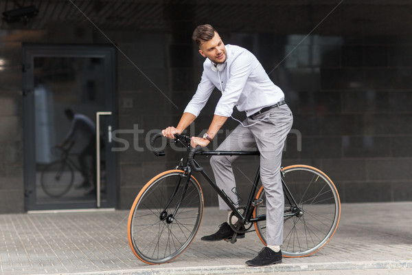 man with bicycle and headphones on city street Stock photo © dolgachov