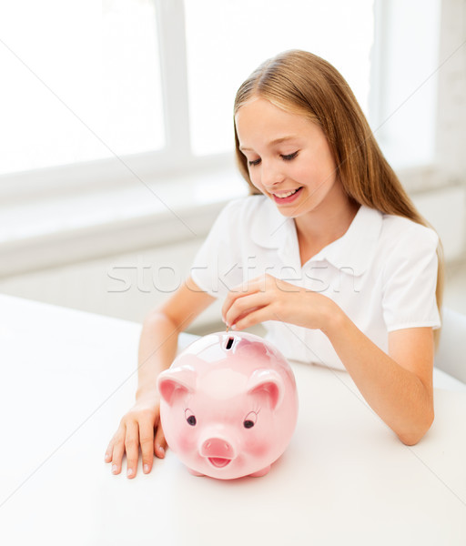 happy smiling girl putting coin into piggy bank Stock photo © dolgachov