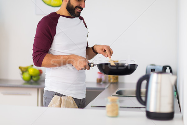 man with frying pan cooking food at home kitchen Stock photo © dolgachov